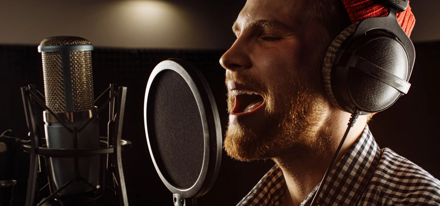 Man speaking into a studio microphone while wearing headphones