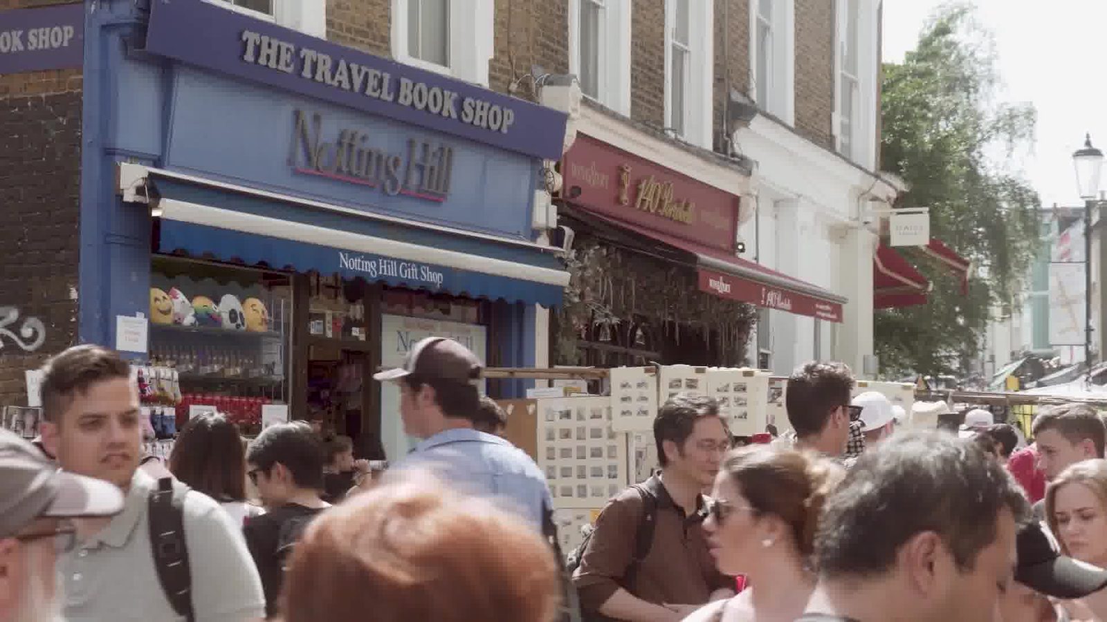 A crowded street in Notting Hill outside The Travel Book Shop, people walking towards the camera