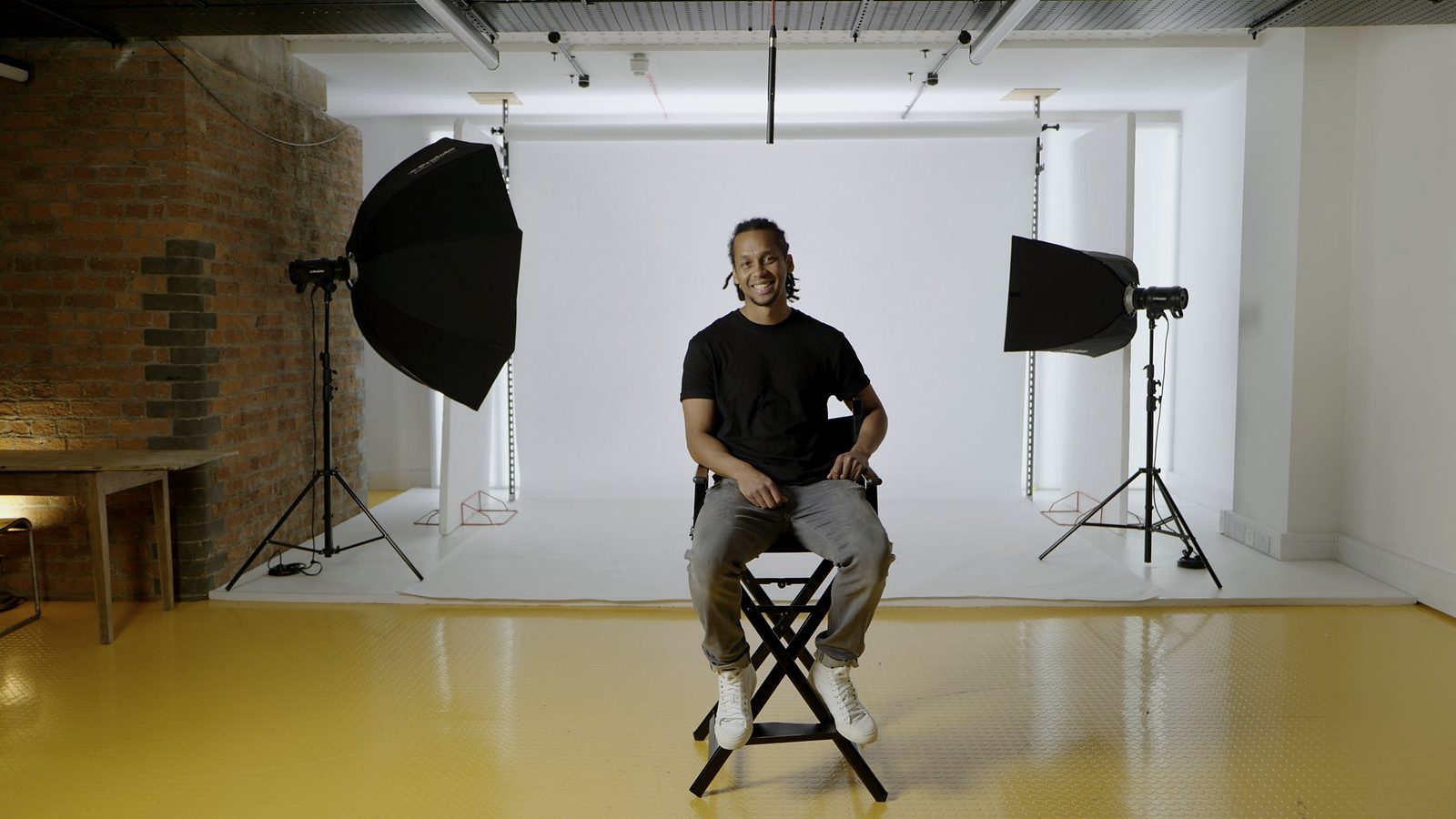 Interview set-up in a white London studio: a contributor on a director’s chair between two softbox lights